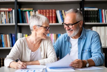 Happy retired couple discussing retirement plans with documents on table